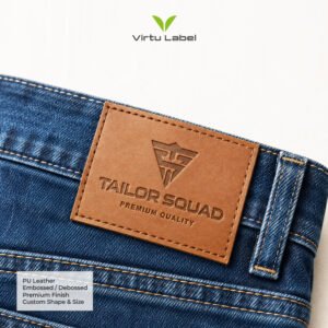 Brown PU leather patch sewn onto denim jeans with embossed Tailor Squad logo