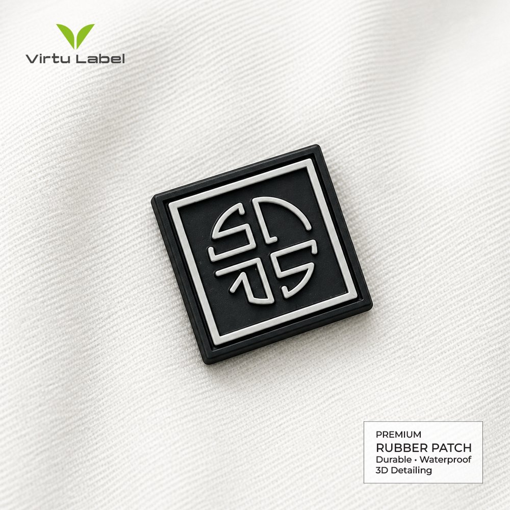 Custom square rubber patch with raised white geometric logo on black PVC base