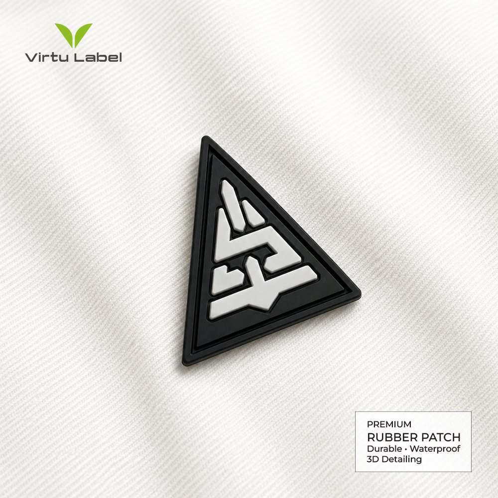 Custom triangular rubber patch with raised white geometric logo on black PVC base