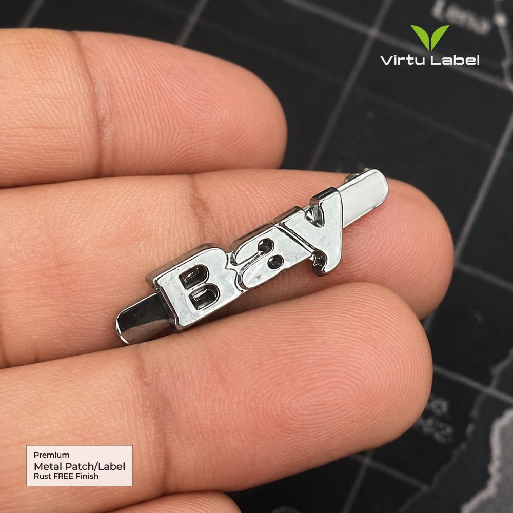 Premium polished silver Bay metal label with raised lettering held between fingers