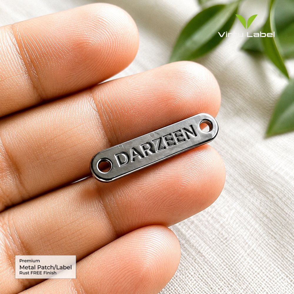 Premium silver Darzeen metal label held between fingers with embossed lettering